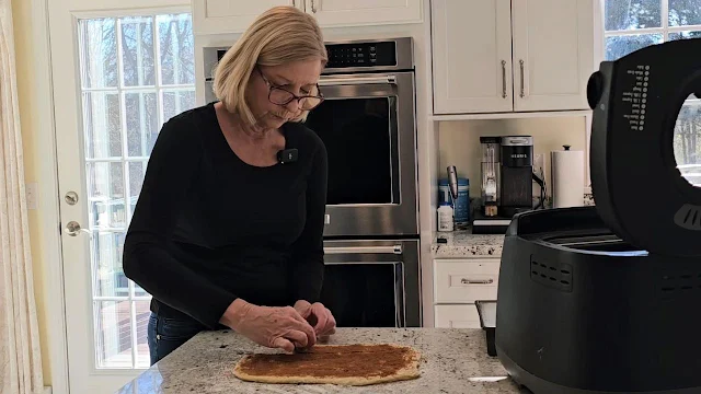 A woman rolling the cinnamon roll dough.