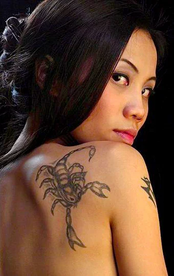 modelo asiatica, de espldas se gira mirandonos sensualmente, lleva en el omoplato un tatuaje de escorpion