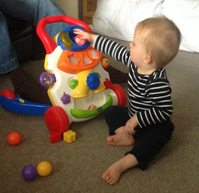 Baby putting ball into hole in toy