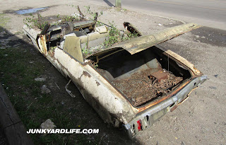 Rear of 1970 Chevy Impala with roof cut off sitting in fron t of Birmingham Alabama scrap yard.