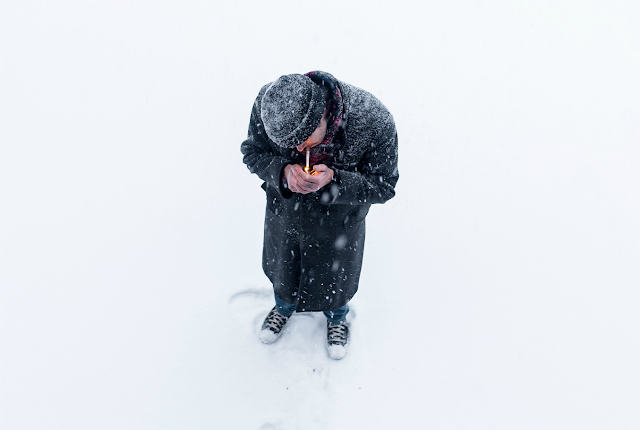 Man trying to light a cigarette, standing in a blizzard