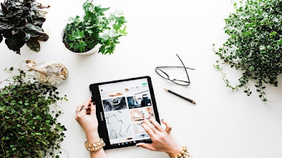 Digital marketing with IPAD around potted flowers, folded eye glasses and a pencil.