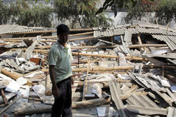 Um habitante de Yingjiang em frente a um edifício destruído depois do tremor de terra (China Daily/ Reuters)