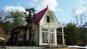 A white house with red roof beside trees in japan