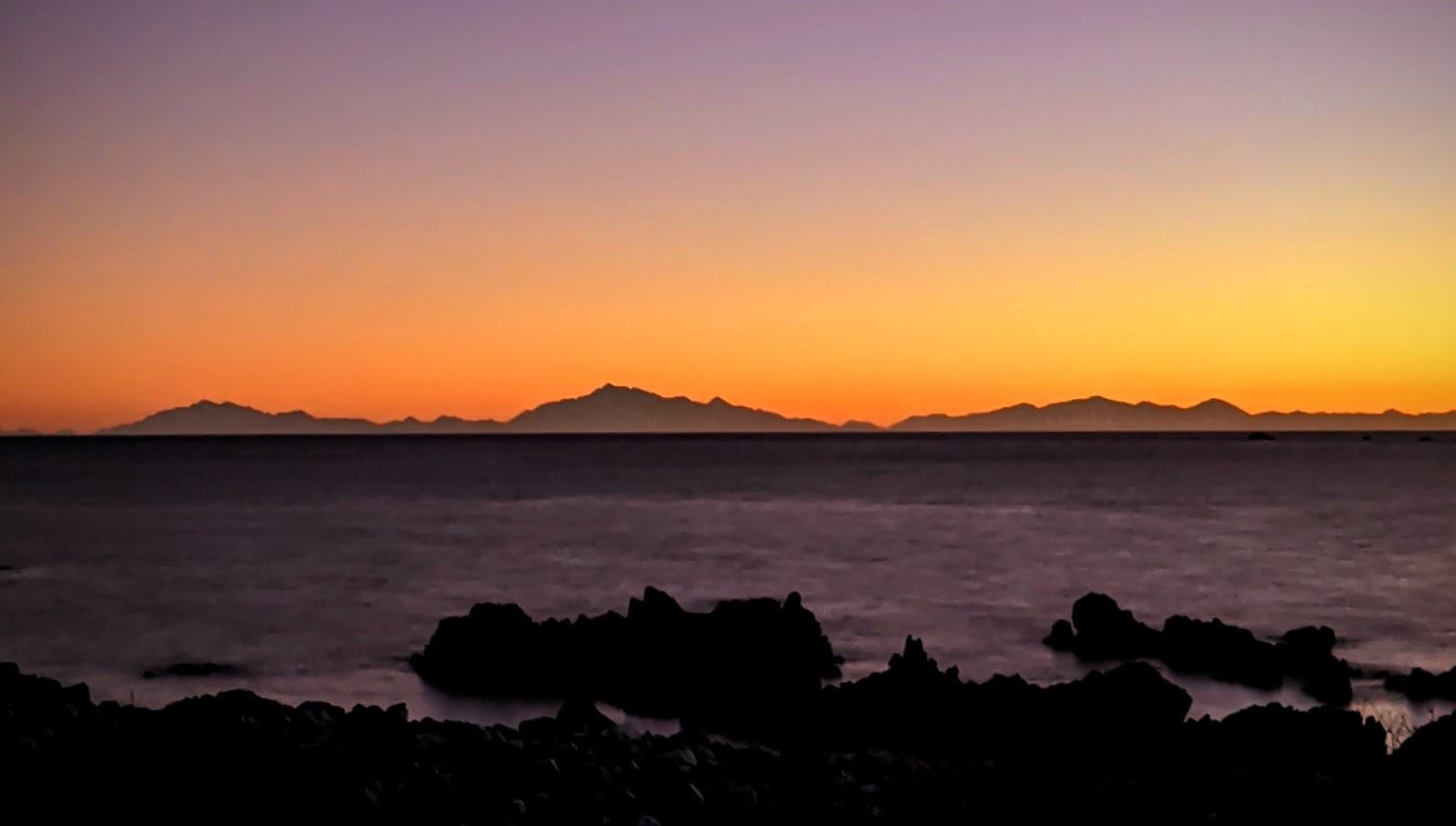 Colourful sunset over Aotearoa New Zealand South Island as seen from Wellington South Coast