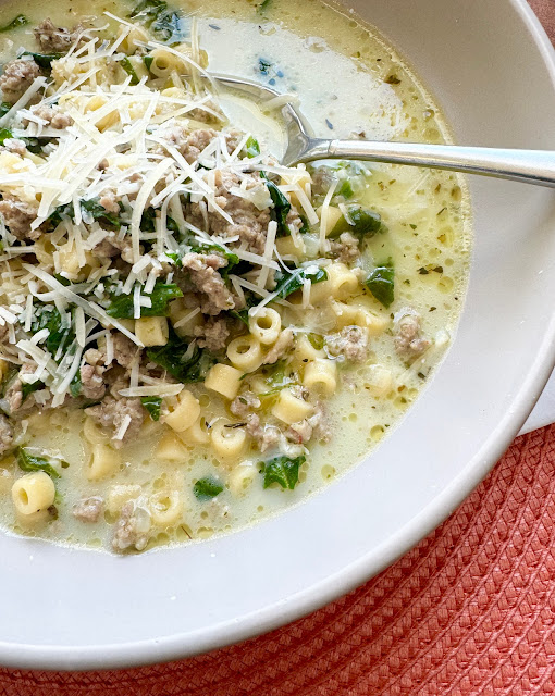 A close up bowl of Sausage Ditalini Soup with a spoon and grated Parmesan cheese.