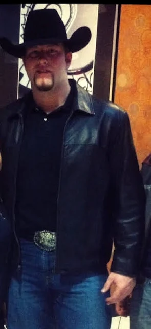 Handsome man wearing a cowboy hat and a black leather jacket with blue jeans on from the waist up