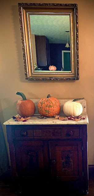 Picture of pumpkins on a cabinet with gold gilt mirror above