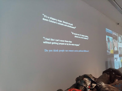 An example of the text displayed behind the statue. Reading from bottom to top, "Do you think people can connect across political differences?" "I feel like I can't move these days without getting jumped on by the woke brigade." "Of course not. It's about making places we can all celebrate." "It's a slippery slope. Should we pull down Colston's schools and almshouses?"