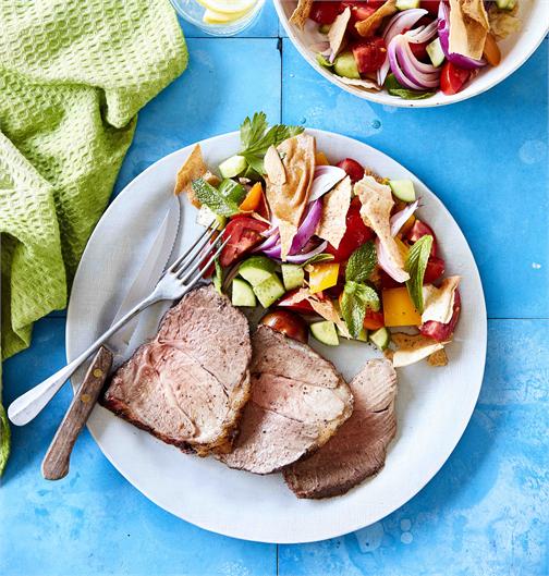 Sumac lamb roast with fattoush salad with fork and knife in a serving dish