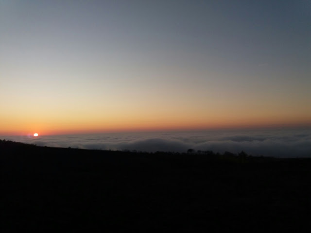 sunset over the sea covered with clouds of fog