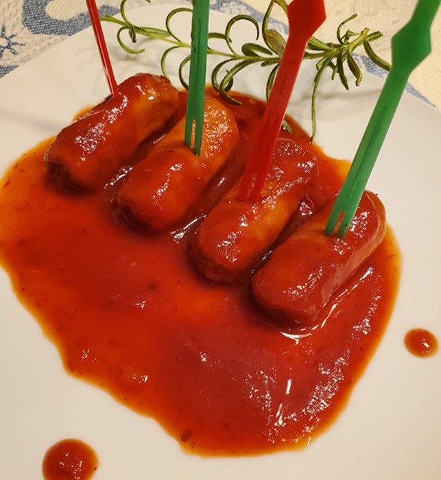 mini sausages or hotdogs in BBQ sauce on a white plate