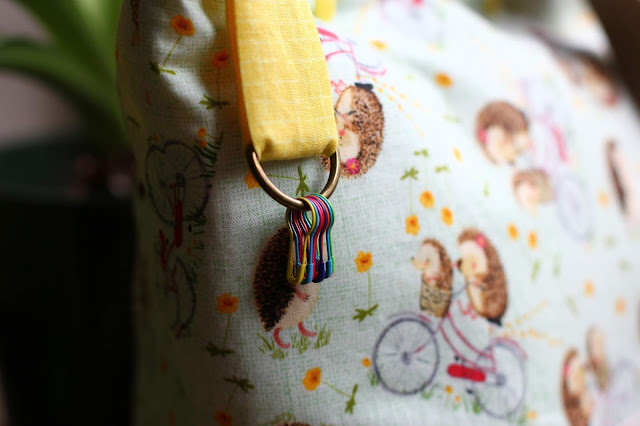 Close-up of yellow loop that has a D-ring with multi-colored removable lightbulb stitch markers.