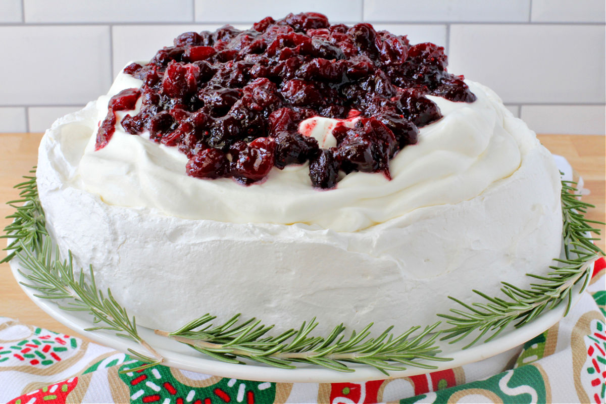 Wintery Pavlova with Port Cranberries and Rosemary on a cake plate waiting to be submitted with school children.