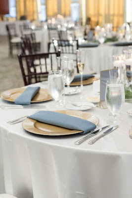 reception tables with gold chargers and blue napkins