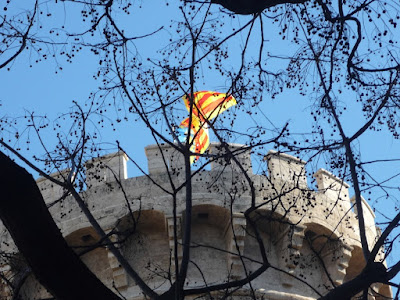 Almenas de las Torres de Quart con la bandera de Valencia al viento, vistas a través de unas ramas