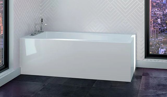 Soaker tub in a white bathroom with black tile floors.
