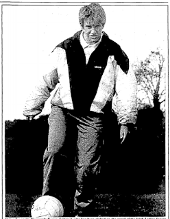 Short-haired woman wearing a shell suit and kicking a football