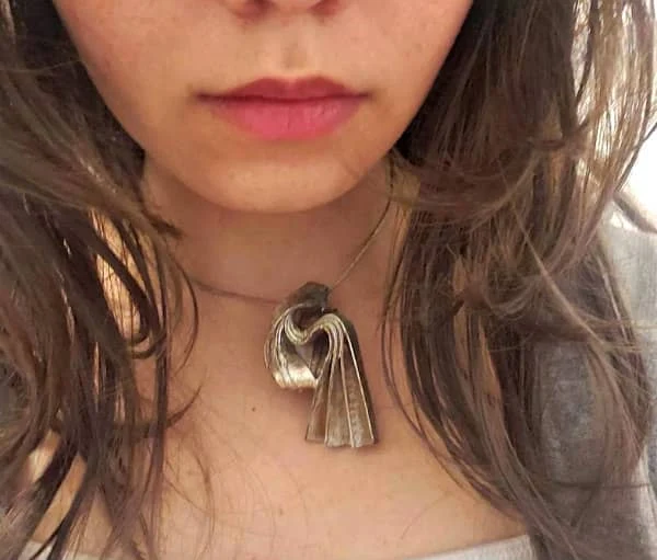 sculptural silver paper pendant on young woman's neck