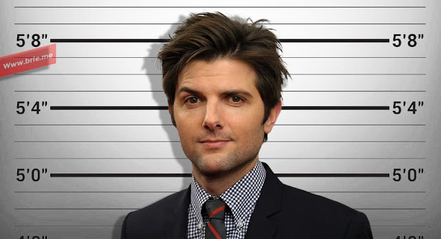 Adam Scott posing in front of a height chart