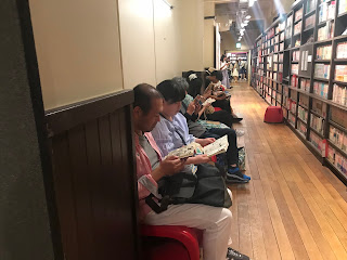 Wall of shelves with people seated before them reading