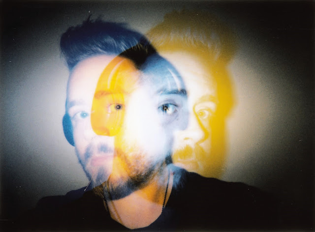 a double exposed selfie. both ghostly and transparent, i'm wearing headphones in both shots, where i'm blue on the left and yellow on the right.