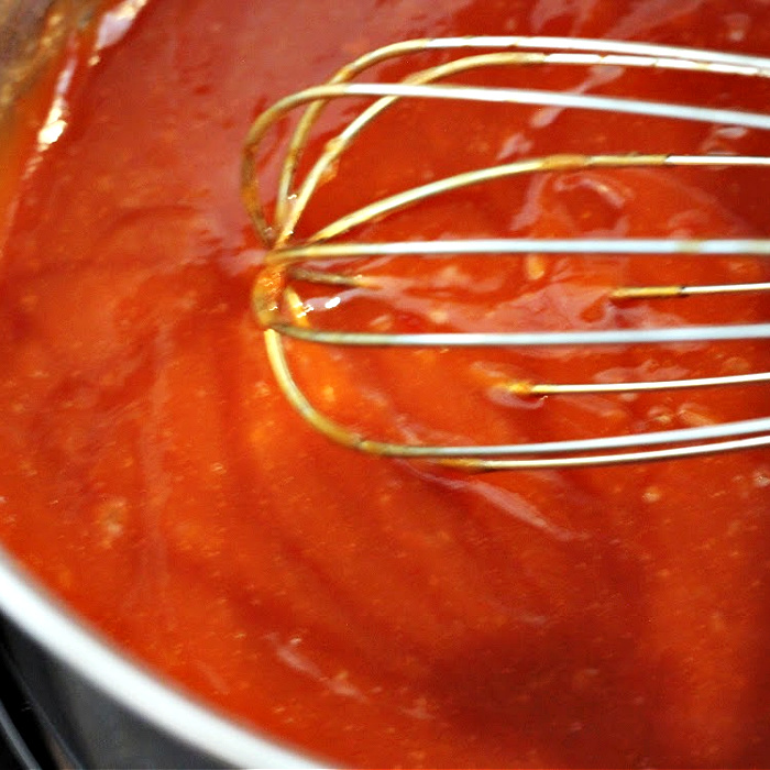 Whisking the Asian bbq sauce for Asian pork meatballs in a large saucepan