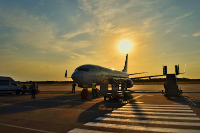 photo of a white aeroplane silhouetted by a sunset