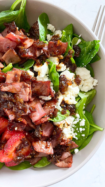 Plate of strawberry spinach salad with feta and hot bacon dressing.