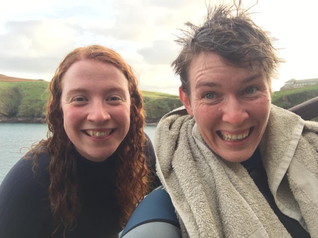 Two people smiling at the camera. They both have wet hair.