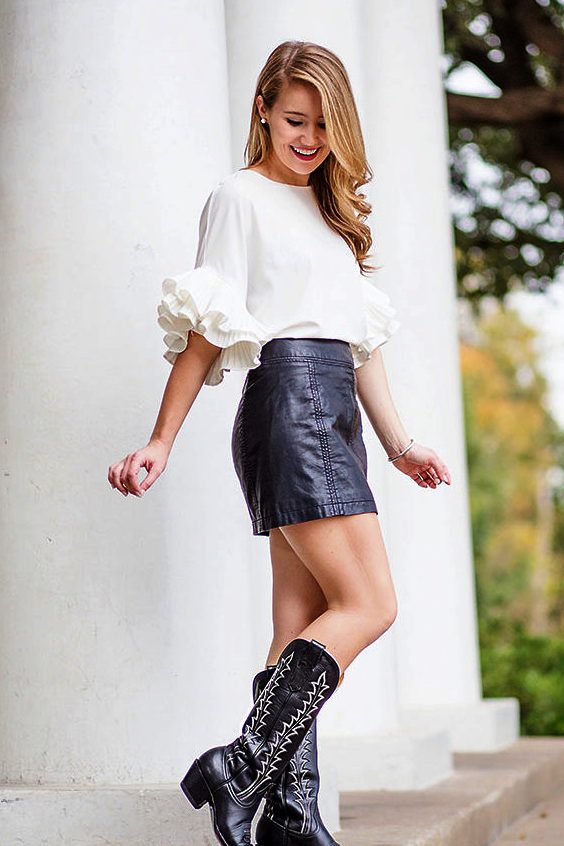 Woman wearing black leather mini skirt and black cowboy boots