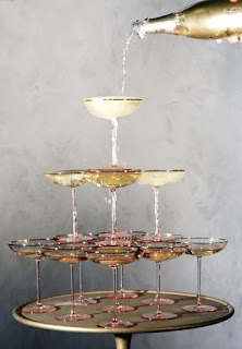 stack of champagne glasses with bottle of champagne pouring from top