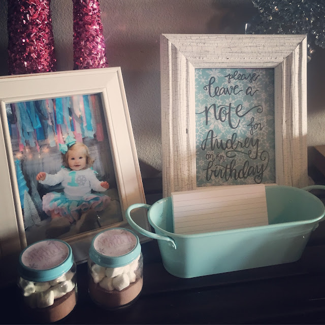 Winter ONEderland 1st birthday party decoration ideas. Food table backdrop and decorations. Hot chocolate and coffee bar chalkboard sign. Winter ONEderland hot chocolate party favors. First birthday outfit