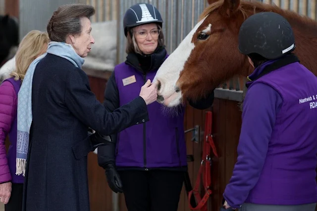 The Princess Royal wore a white trench coat, gold brooch at Reaseheath Equestrian College