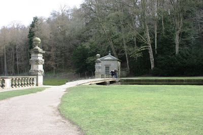 Photo showing narrow wooden footbridge, with no railings, over the lake