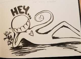 A photograph of a pen drawing in a sketchbook. The drawing is of a stylized monster, with a round head and no facial features except large teeth. The figure is reclining, with the text "HEY..." above it's head. It has a heart on it's chest, and it's hand is forming the shape of a heart.