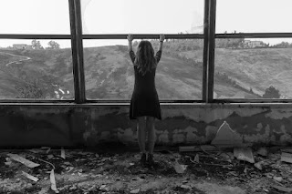 An image of a girl standing on the window in the black dress- sad girl dp