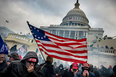 color photograph by David Butow of Supporters of President Donald Trump retreating  from tear gas during a battle with Law Enforcement officers on the west steps of the Capitol in Washington, January 6, 2021