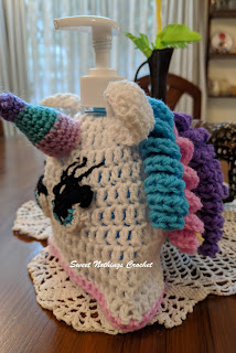 Sweet Nothings Crochet free crochet pattern blog, free crochet pattern for a unicorn soap dispenser bottle cover, this blog has video tutorials, photo with detail of eyelashes for unicorn on right side of face,