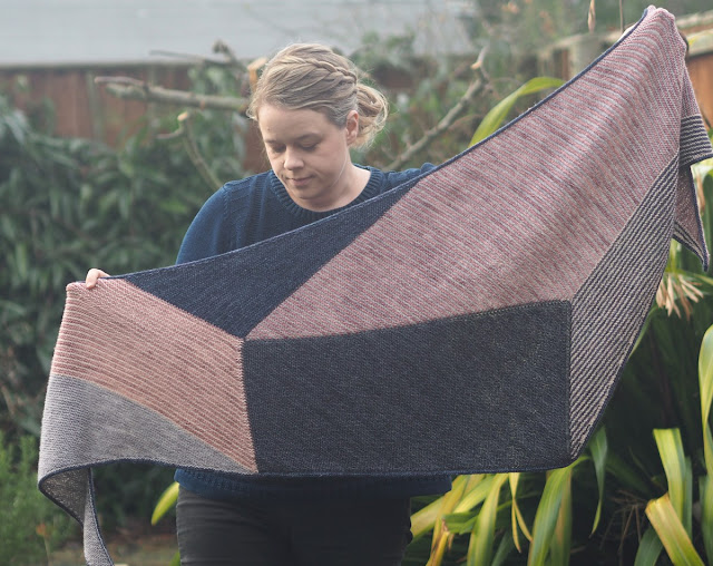 woman holding up a multi-coloured garter stitch shawl