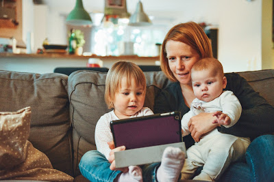 Madre con un bebé y un niño pequeños manejando una tablet