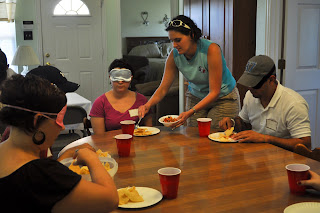 View of our table as a guide dog instructor spoons some salsa onto my plate, in the corner you can see Erin serving herself chips from a big bowl that was passed around