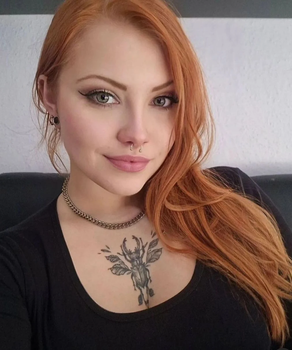 Foto de una preciosa joven modelo pelirroja con tatuaje de un afortunado escarabajo en el pecho