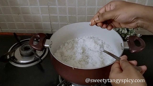 The rice simmering in the pan, absorbing all the water and becoming perfectly tender and fluffy for Puliogare. The cooking process takes around 15-20 minutes, with variations based on the rice type used.