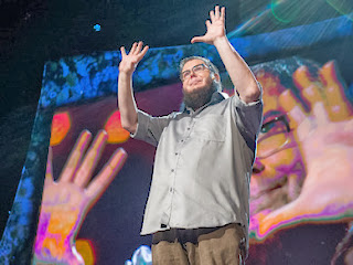 picture of Shane Koyczan holding up his hands 