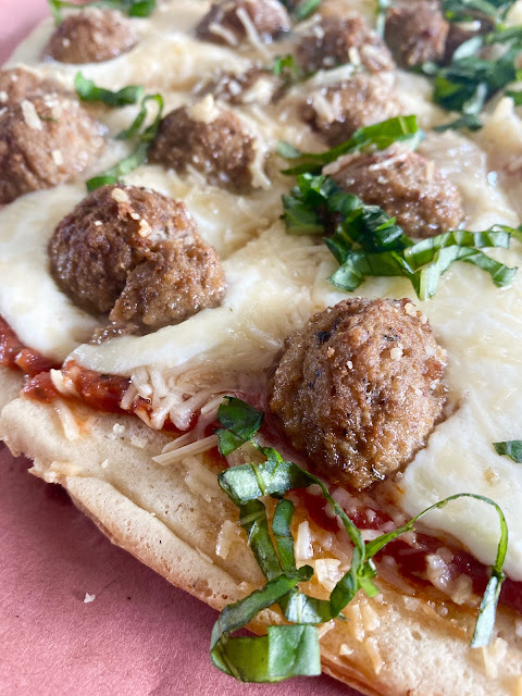 Close up shot of finished Grilled Meatball Pizza cut into slices.