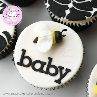 Closeup of cake topper with the word, Baby on it and a gumpaste bee next to it.