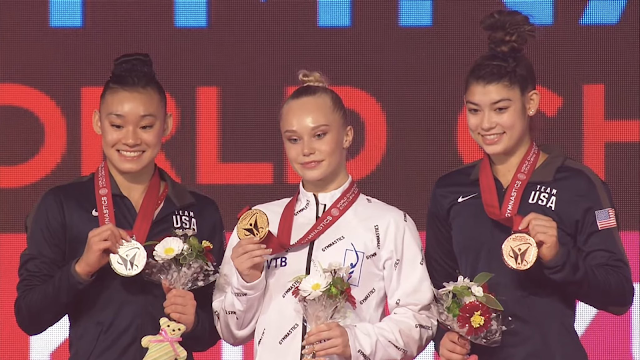 Wong, Melnikova e di Cello posam para foto segurando suas medalhas e um buquê de flores