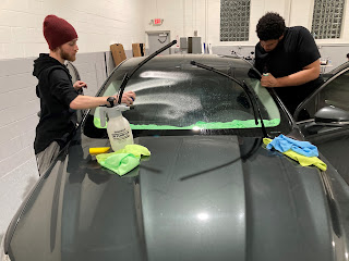 Two men applying window tinting to a car in Livonia