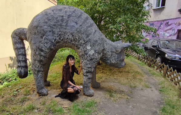 Moje zdjęcie w czarnej sukience pod figurom wielkiego szarego kota. Wrocłw - Kolorowe Podwórka